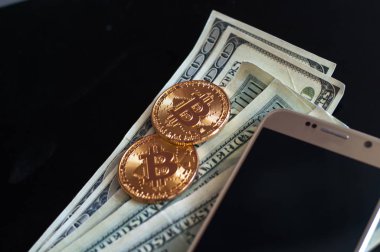 bitcoin ve dolar ve cep telefonu siyah arka plan üzerine iki altın sikke