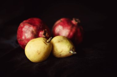 parlak, olgun pomogranate ve siyah arka plan üzerine armut