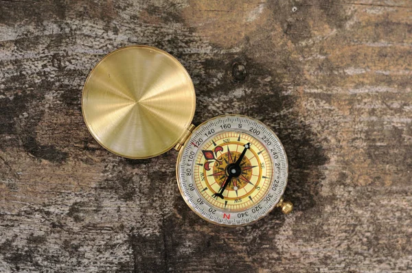 Golden vintage compass on wooden background with natural light — Stock Photo, Image