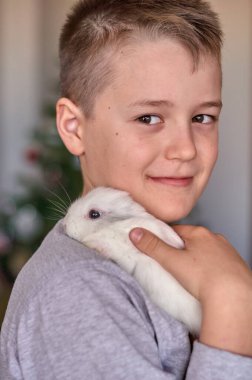 Elinde beyaz bir tavşan olan bir çocuk.