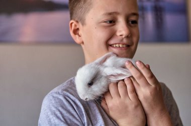 Elinde beyaz bir tavşan olan bir çocuk.