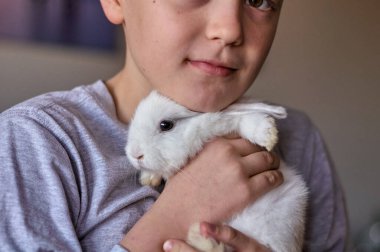 Elinde beyaz bir tavşan olan bir çocuk.