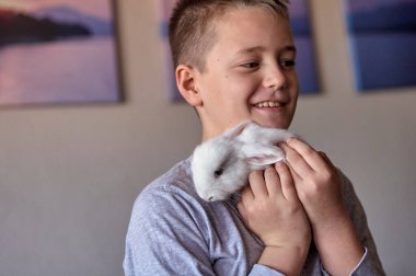 Elinde beyaz bir tavşan olan bir çocuk.