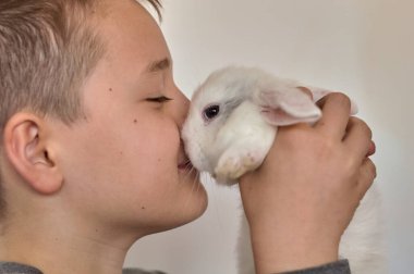 Elinde küçük beyaz bir tavşan olan çocuk.