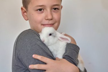 Elinde küçük beyaz bir tavşan olan çocuk.