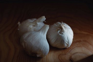 Tahta bir tahtanın üzerinde üç sarımsak kafası.