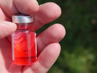 Elinde ilaç olan kırmızı şişe.