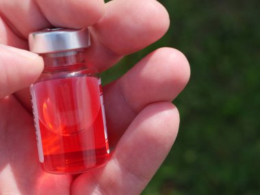 Elinde ilaç olan kırmızı şişe.