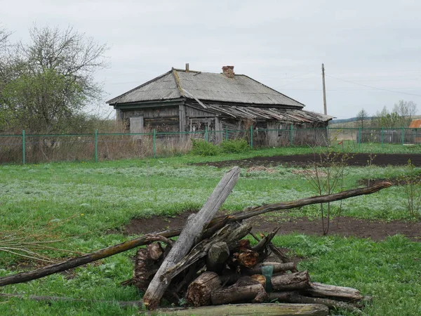 旧原木躺在草地上 远处是一座村舍 — 图库照片