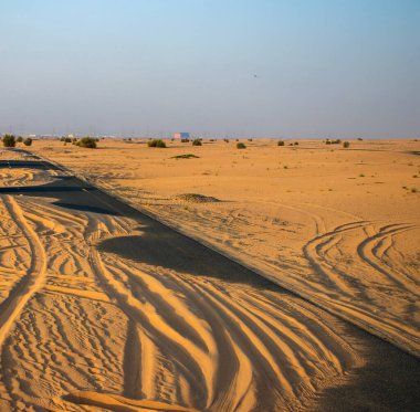 Terk edilmiş asfalt yolu kumla kaplı.