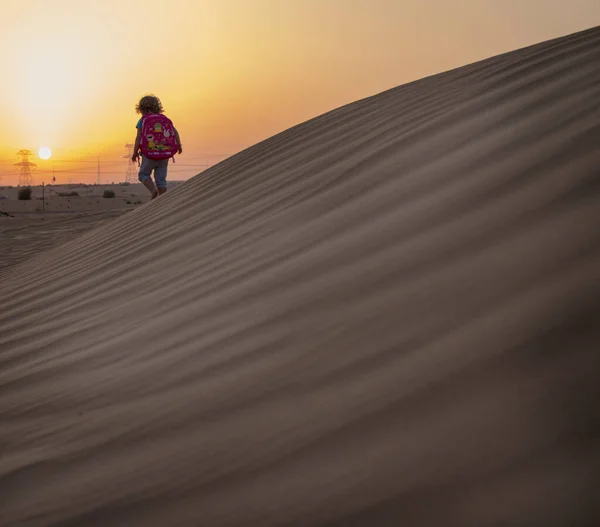 Kid walking towards the sunset in the desert