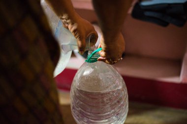 Bir varil sudan evcil hayvan şişesine su döken bir adam.