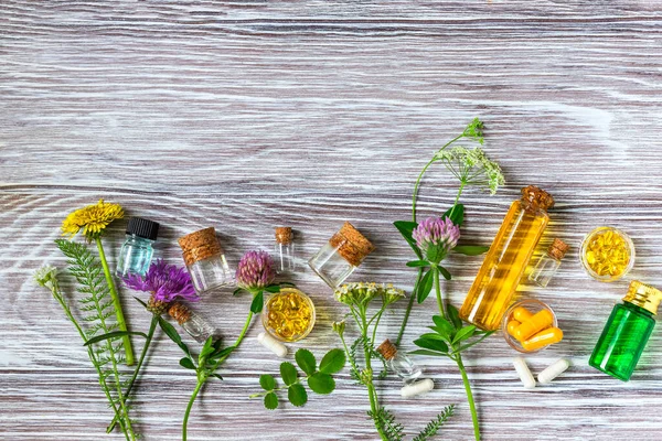 Medical flowers herbs essential oils in bottles for natural diseases treatment on wooden table. Concept of natural cosmetics. Space for text.