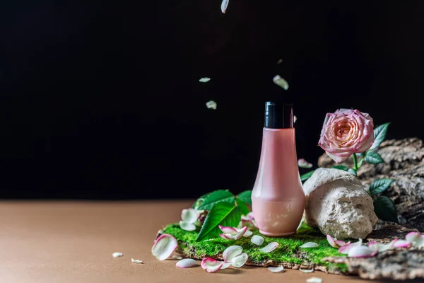 Pink tube of cosmetic product on a creative stone podium on a dark background. Trendy natural spa concept.