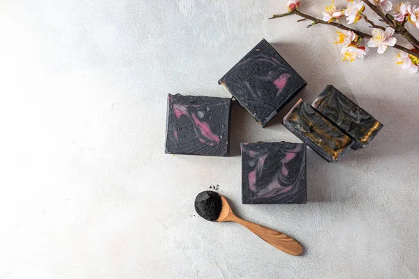 Bars of handmade organic soap with charcoal on a light background. Blackcurrant sorbet. Selective focus, copy space