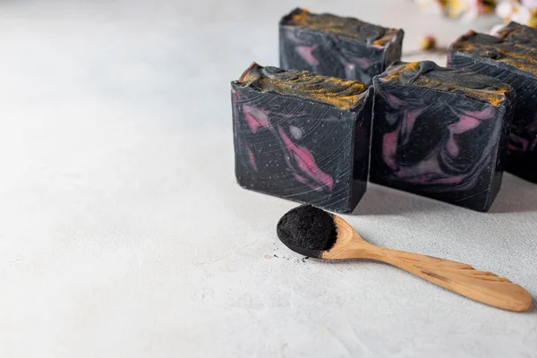 Bars of handmade organic soap with charcoal on a light background. Blackcurrant sorbet. Selective focus, copy space