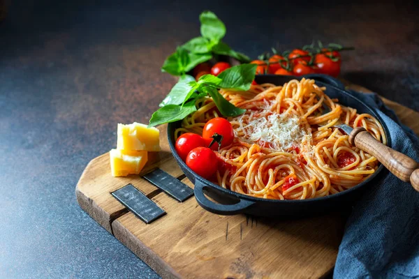 Spaghetti, pasta with tomato sauce and cherry tomatoes with basil on a dark background. Selective focus, copy space