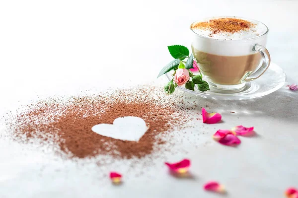 Cappuccino and heart made of cocoa powder on white background. The idea for a festive breakfast, Valentine\'s Day. Selective focus, copy spacy