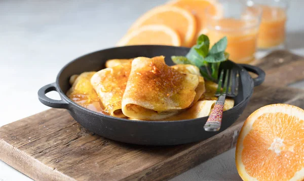 Crepes with Orange Sauce in a cast iron pan. Traditional French crepe Suzette with orange sauce. Selective focus, top view