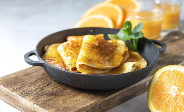 Crepes with Orange Sauce in a cast iron pan. Traditional French crepe Suzette with orange sauce. Selective focus, top view