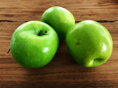 Bir ahşap yüzeyde üç yeşil elmaya yakın çekim