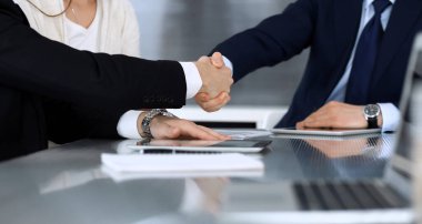 Modern ofiste cam masada çalışırken iş adamları el sıkışıyor. Bilinmeyen bir iş adamı, iş arkadaşı olan bir erkek girişimci. Takım çalışması, ortaklık ve el sıkışma kavramı.