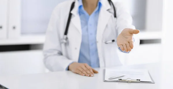 Unknown woman-doctor in blue blouse is giving helping hand while sitting at the desk in clinic. Perfect medical service, medicine concept — Stock Photo, Image