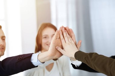 Takım çalışması yapan ve el ele tutuşan iş adamları grubu ya da güneşli bir ofiste beş kişi. Bilinmeyen işadamı ve kadınlar elleriyle daire çiziyorlar.