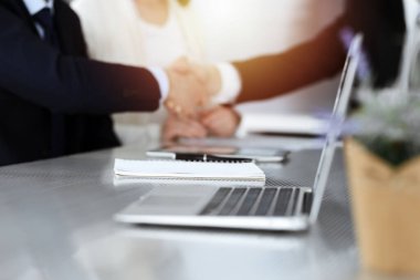 İş adamları güneşli modern ofiste kontrat imzalandıktan sonra el sıkışıyor. Takım çalışması ve el sıkışma kavramı