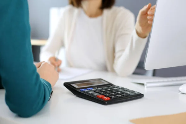 Contabilista verificando ficha financeira ou contando por calculadora de renda para a forma de imposto, mãos close-up. Mulher de negócios sentada e trabalhando com colega na mesa no escritório. Conceito de auditoria — Fotografia de Stock