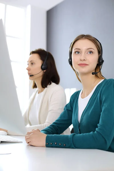 Centro de llamadas. Grupo de operadores en el trabajo. Enfócate en la hermosa recepcionista en auriculares en la oficina de servicio al cliente. Concepto empresarial —  Fotos de Stock