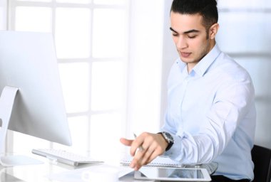 Modern ofiste bilgisayarla çalışan bir iş adamı. Arap erkek girişimcinin ya da iş yerindeki müdürün vesikalığı. İş konsepti