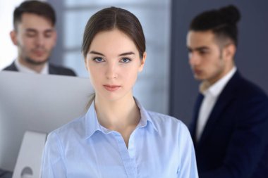 Modern ofisin arka planında iş kadını ve çeşitli iş adamları var. Çok ırklı takım çalışması ve iş konsepti