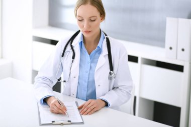 Hastane bürosundaki masada otururken ilaç kayıtlarını dolduran doktor kadın. Hekim kadın iş başında. Tıp ve sağlık alanlarındaki veriler