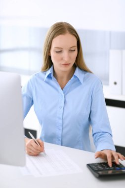 Muhasebeci mali durumu kontrol ediyor ya da hesap makinesi geliri ile vergi formunu sayıyor. Ofisteki masada oturan ve çalışan bir iş kadını. Denetim kavramı