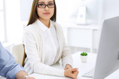 İş kadını ve erkek ofiste bilgisayar başında oturuyor ve çalışıyor. İş arkadaşları toplantıda bir şey tartışıyor. Şirket takım çalışması ve ortaklık kavramları