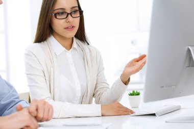 İş kadını ve erkek ofiste bilgisayar başında oturuyor ve çalışıyor. İş arkadaşları toplantıda bir şey tartışıyor. Şirket takım çalışması ve ortaklık kavramları