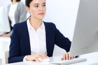 Ofiste bilgisayarla çalışan bir iş kadını, arka planda çalışan bir iş arkadaşı. Masada otururken avukatın ya da muhasebecinin vesikalığı.