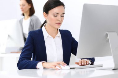 Ofiste bilgisayarla çalışan bir iş kadını, arka planda çalışan bir iş arkadaşı. Masada otururken avukatın ya da muhasebecinin vesikalığı.