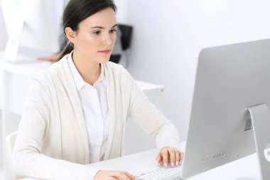 Ofiste bilgisayarla çalışan bir iş kadını, arka planda çalışan bir iş arkadaşı. Masada otururken avukatın ya da muhasebecinin vesikalığı.