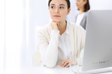 Ofiste bilgisayarla çalışan bir iş kadını, arka planda çalışan bir iş arkadaşı. Masada otururken avukatın ya da muhasebecinin vesikalığı.