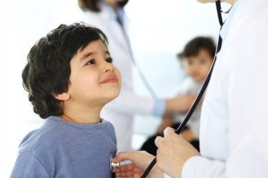 Doktor steteskopla çocuk bir hastayı muayene ediyor. Doktor randevusunda tatlı bir Arap çocuk. Tıp ve sağlık hizmetleri kavramı