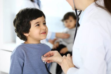 Doktor steteskopla çocuk bir hastayı muayene ediyor. Doktor randevusunda tatlı bir Arap çocuk. Tıp ve sağlık hizmetleri kavramı