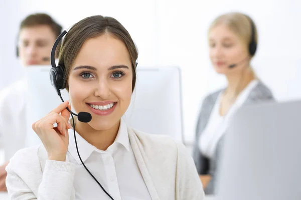 Centro de llamadas. Grupo de operadores en el trabajo. Enfócate en la hermosa recepcionista en auriculares en la oficina de servicio al cliente de color blanco. Concepto empresarial — Foto de Stock