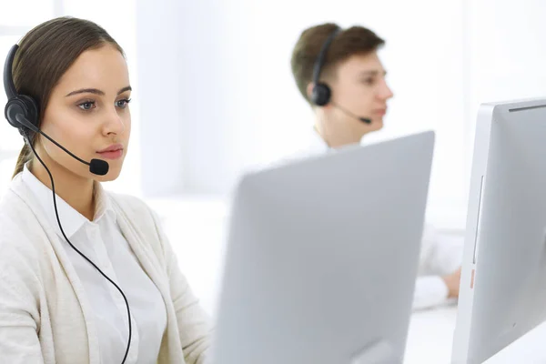 Centro de llamadas. Grupo de operadores en el trabajo. Enfócate en la hermosa recepcionista en auriculares en la oficina de servicio al cliente de color blanco. Concepto empresarial —  Fotos de Stock