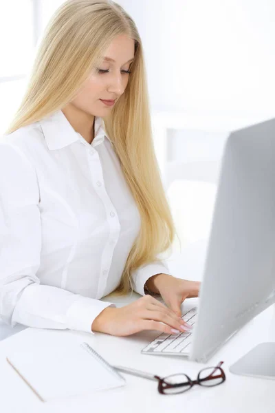 Mujer de negocios rubia sentada y trabajando con computadora en oficina blanca. Estudiante chica estudiando o secretaria haciendo informe. Concepto de éxito —  Fotos de Stock