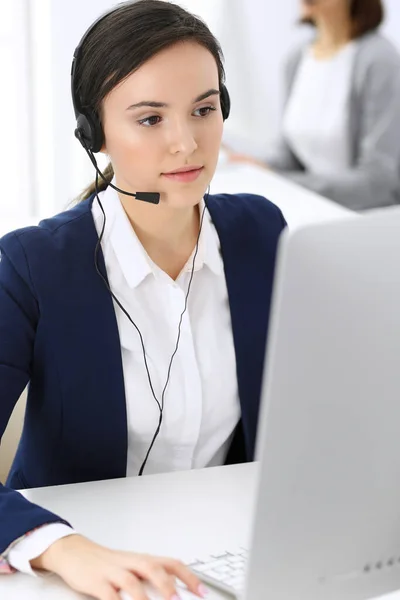 Centro de atendimento. Mulher bonita recepcionista sentado no fone de ouvido no escritório de atendimento ao cliente. Grupo de operadores a trabalhar. Conceito de negócio — Fotografia de Stock