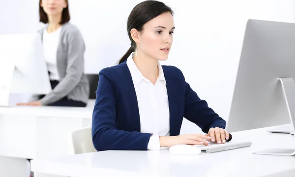 Mujer de negocios que trabaja con la computadora en la oficina, colega de fondo. Imagen de Abogado o Contador en el trabajo mientras está sentado en el escritorio —  Fotos de Stock