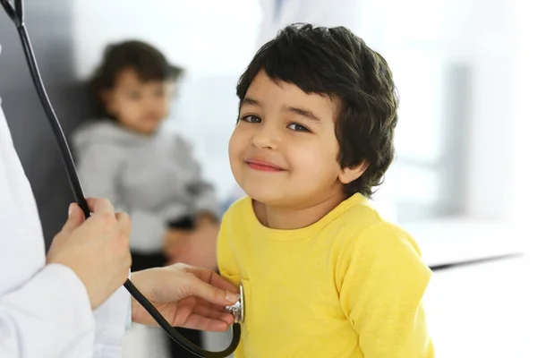 Médico examinando a un niño paciente por estetoscopio. Lindo chico árabe en la cita con el médico. Concepto de medicina y salud —  Fotos de Stock