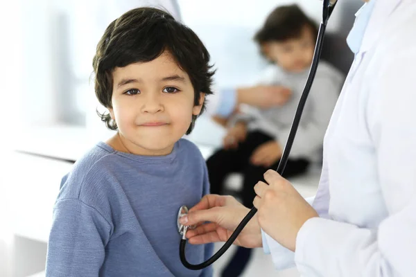 Врач осматривает ребенка стетоскопом. Милый арабский мальчик на приеме у врача. Медицина и здравоохранение — стоковое фото